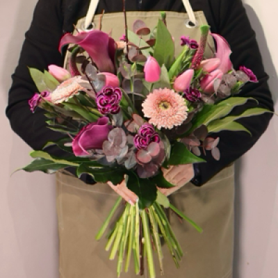 Plum and Blush - This elegant arrangement features a luxurious mix of blooms, including deep plum calla lilies, soft pink gerberas, vibrant tulips, and beautifully textured accent flowers. Lush green foliage and dusky eucalyptus add natural movement and depth, creating a bouquet that feels both modern and romantic.
